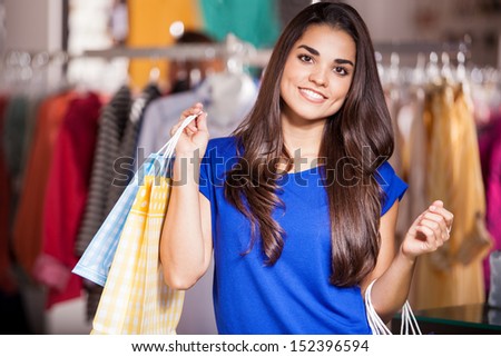 Cute young woman carrying some shopping bags and doing some shopping in a clothing store