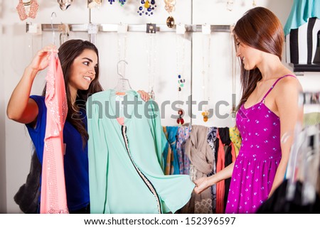 Cute girl helping her friend decide on which blouse would look better on her