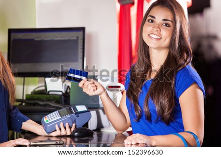 Beautiful Hispanic woman paying with a credit card at a clothing store