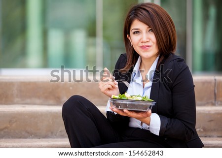 Cute business woman eating a healthy salad and relaxing outdoors