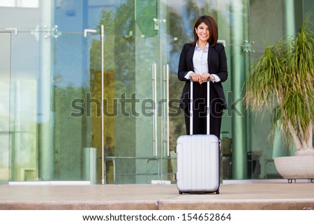 Happy Hispanic - Asian businesswoman at an airport carrying a suitcase