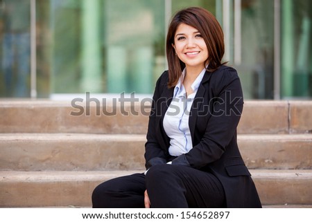 Happy female business school student sitting outside and relaxing