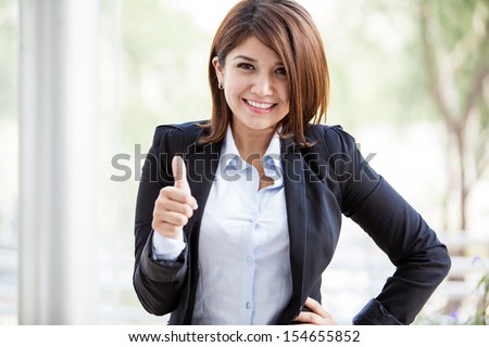 Happy Hispanic business woman on a suit giving a thumb up in a sign of approval