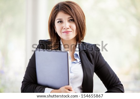 Portrait of a beautiful Hispanic - Asian business school student carrying a laptop computer