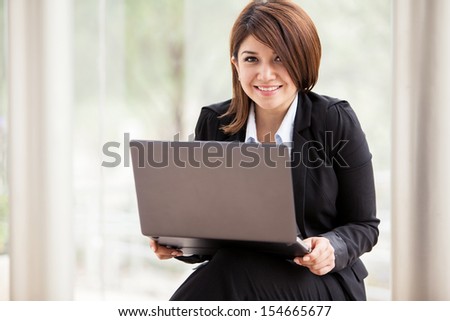 Cute female business school student doing some with a laptop computer and smiling