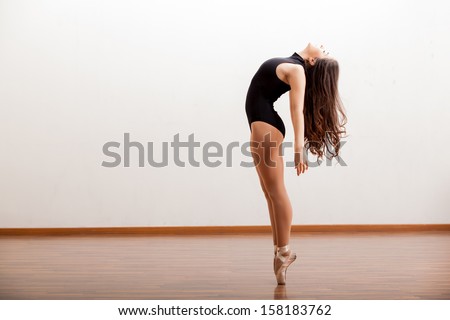 Gorgeous ballet dancer maintaining balance during a dance routine in a studio