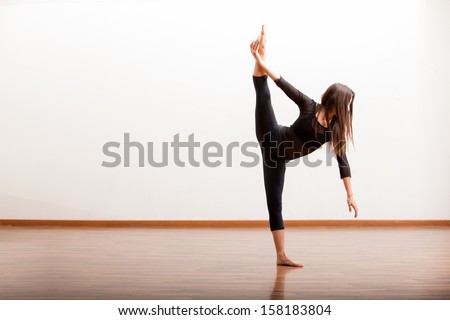 Pretty Hispanic female jazz dancer practicing some dance moves in a dance academy