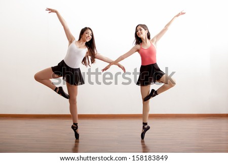 Pretty Hispanic ballet dancers practicing a routine in a dance academy and smiling
