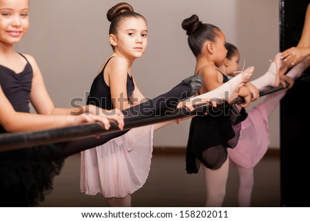 Cute little ballet dancers practicing some dance moves in a barre in a dance class