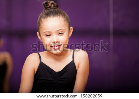 Portrait of a beautiful little girl wearing a ballet outfit and smiling in a dance studio