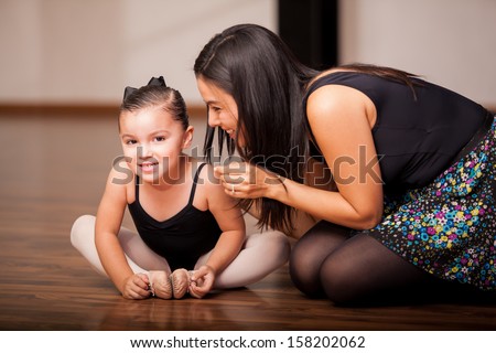 Cute little girl and her dance instructor smiling and having fun during class