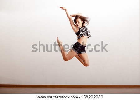 Beautiful jazz dancer jumping during a dance rehearsal in a studio
