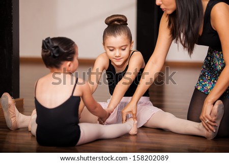 Two little girls warming up and getting instructions by their dance instructor in a dance academy