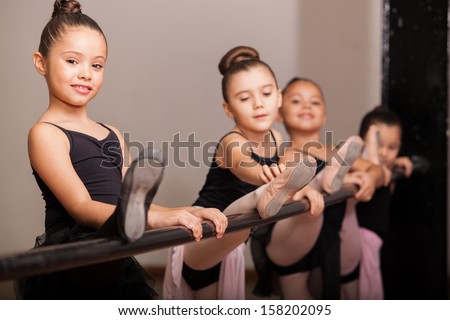 Cute little girl loving her ballet class and raising her leg on a ballet barre