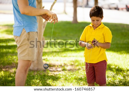 Cute kid learning how to play with a yo-yo with his father