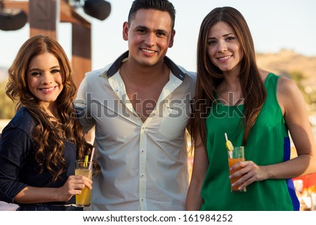 Portrait of a young handsome man hanging out and having drinks with two female friends