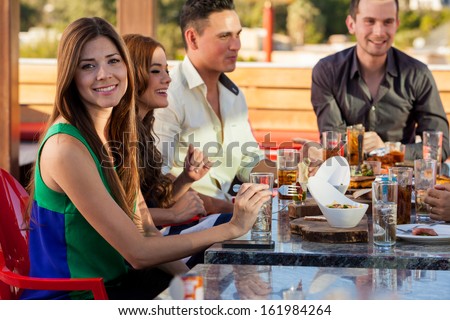 Beautiful young woman and her friends eating out and having a few drinks at a restaurant outdoors