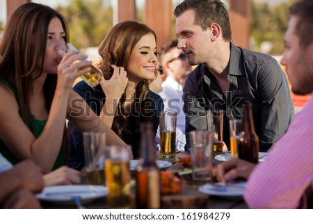Young couple flirting with each other while hanging out with some other friends at a restaurant