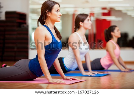 Cute Hispanic Women Practicing The Cobra Pose During Their Yoga Class In A Gym
