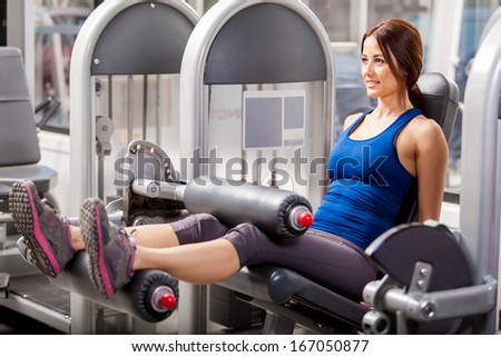Cute young brunette building leg muscles in a simulator at the gym