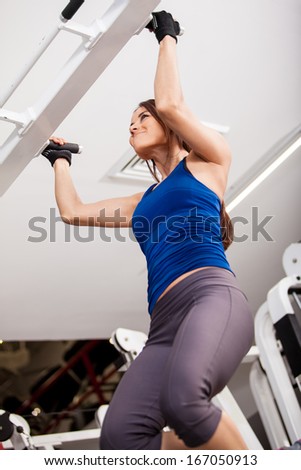 Very athletic young woman doing some bar pull ups at the gym. Shot from a low angle