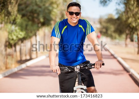 Happy young man riding a bicycle and wearing sunglasses on a sunny day