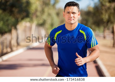 Athletic Latin man training and working out in a running track on a sunny day