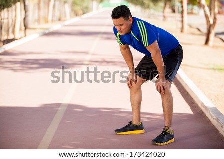 Fit Hispanic runner stopping for a moment to get some air after a long run
