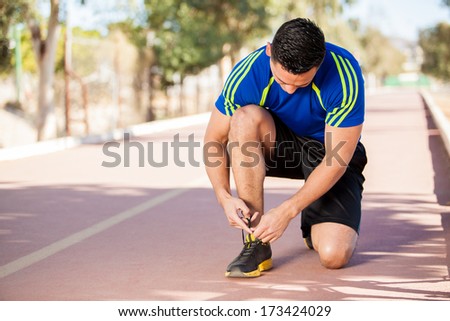 Strong young man tying his shoes before going for a run at the track