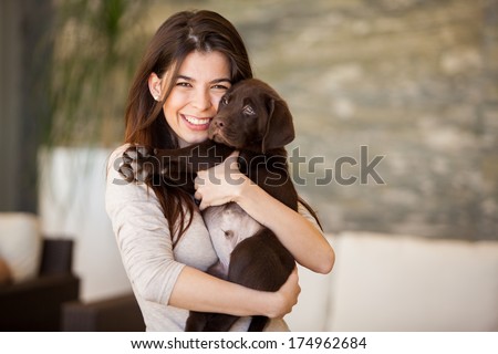 Beautiful young woman hugging and showing some love to his puppy at home