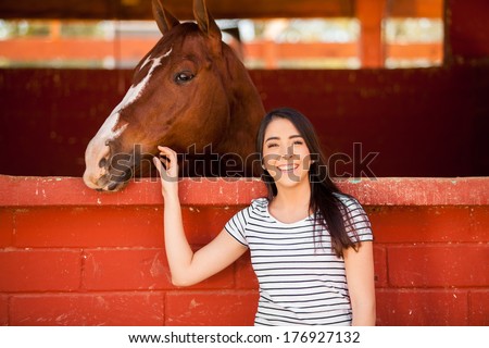 Cute Hispanic woman spending some time with a horse at the stables