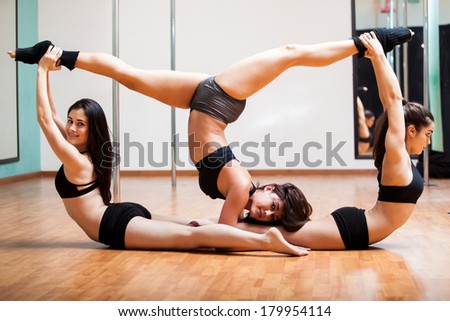 Group of beautiful women taking stretching to a whole new level in a pole dancing class