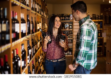 Portrait of a young Hispanic couple buying some wine bottles in a supermarket