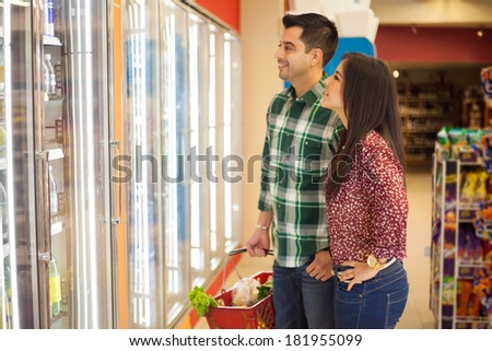 Portrait of a young beautiful couple in front of a few refrigerators and buying some frozen food