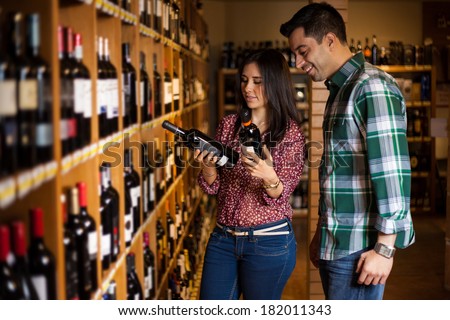 Cute young Hispanic couple trying to decide which bottle of wine to buy among so many options