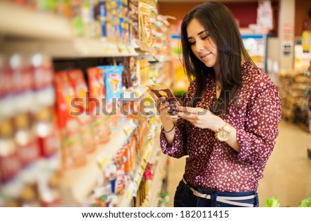 Cute young woman examining a product label while shopping at the store