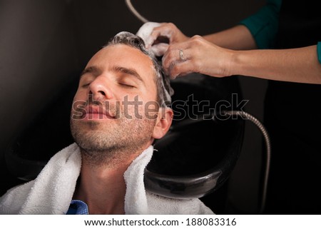 Relaxed young man getting his hair washed before getting a haircut at a salon