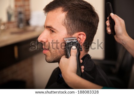 Young man getting his sideburns trimmed at a barber shop