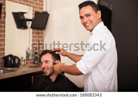 Happy young barber trimming a client\'s sideburns and loving his job