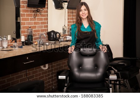 Gorgeous young woman standing behind a salon chair and greeting customers to her hair salon