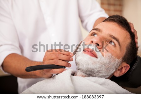 Closeup of a young man getting a close shave at a barber shop
