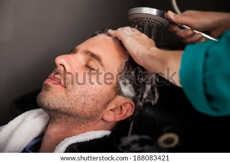 Young Hispanic man getting pampered with a hair wash and head massage in a hair salon
