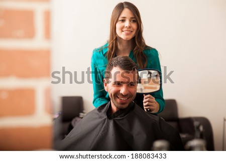 Happy customer looking at himself in a mirror after getting a haircut in a barber shop