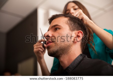 Young man getting his hair cut by a lady barber in a barber shop