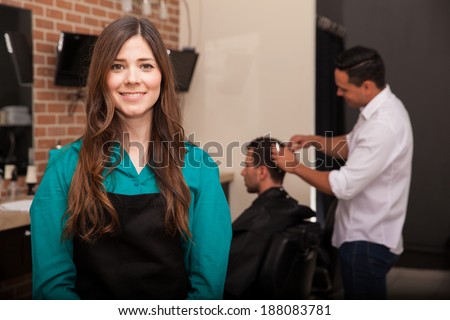 Cute young woman managing her barber shop and smiling