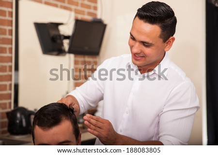 Young Latin barber giving a haircut to a client