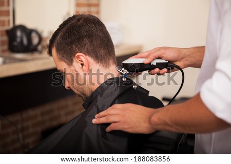 Male hairstylist using hair clippers on a customer at a hair salon