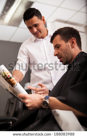 Young man trying to find a new look for him on a magazine at a barber shop