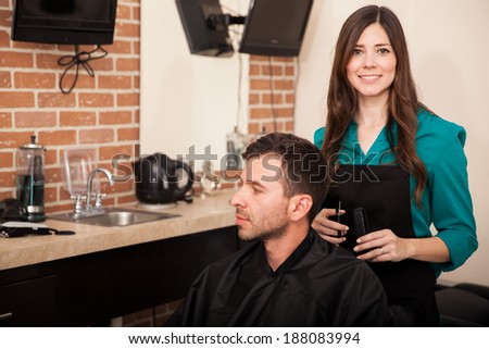 Beautiful hairstylist cutting a man\'s hair at a hair salon