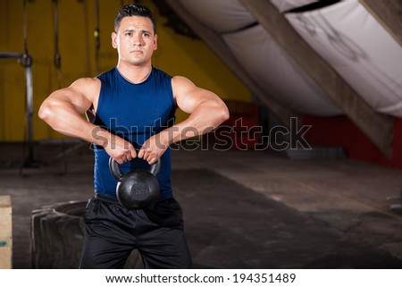 Young Hispanic man working out by lifting a kettlebell in a cross-training gym